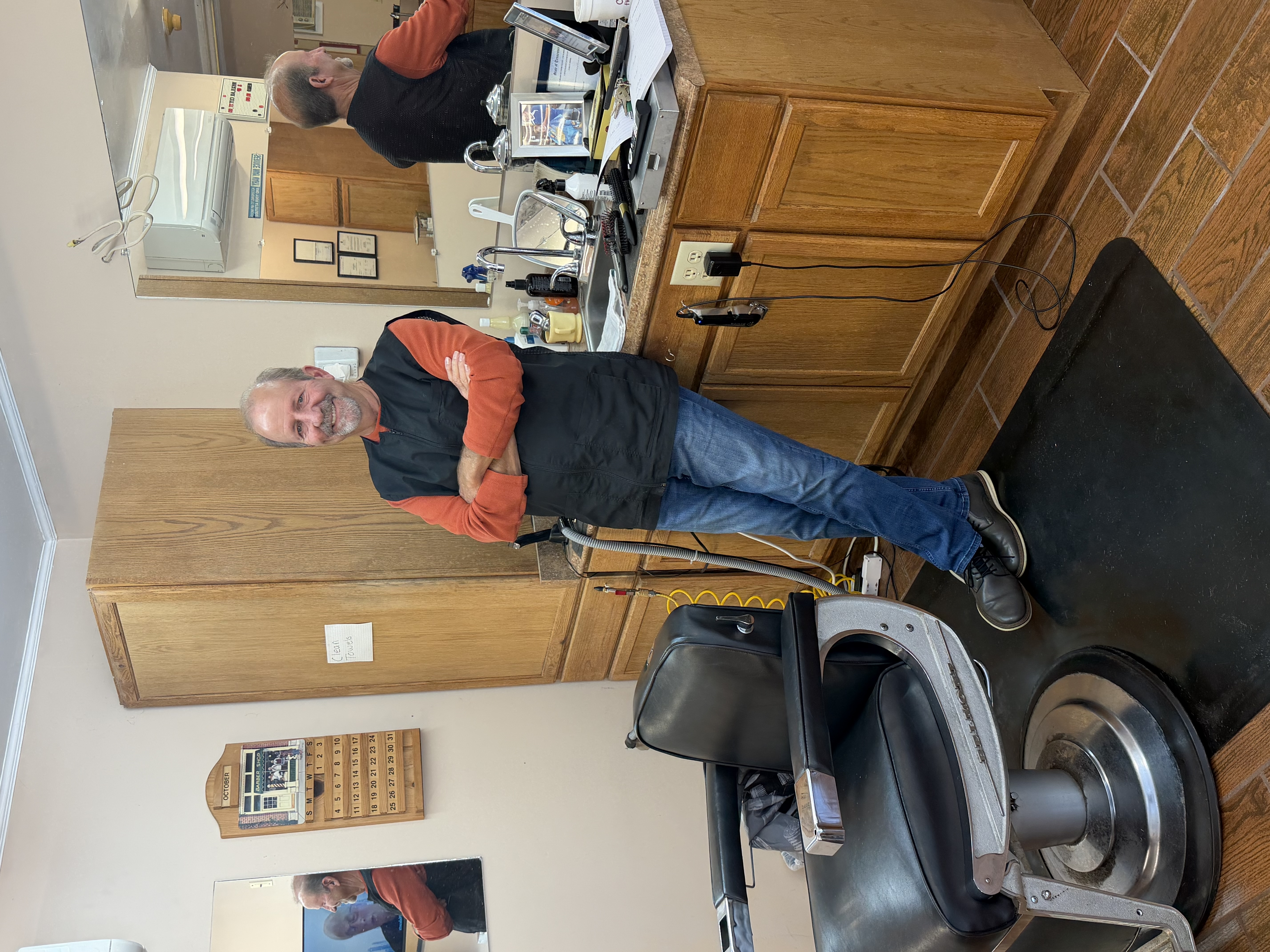 Wes Norris, owner of Lee Highway Barber & Style Shop, leaning against the counter beside his barber chair